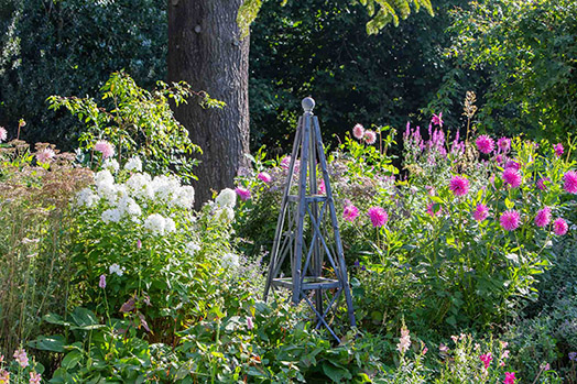An Arthur Jack small steel obelisk pictured in a garden